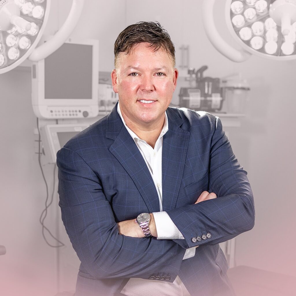 Dr. Oliver Pope Simmons, MD, Plastic and Reconstructive surgeon at BeautyLand Plastic Surgery Miami, is pictured posing with arms crossed and smiling for a picture.