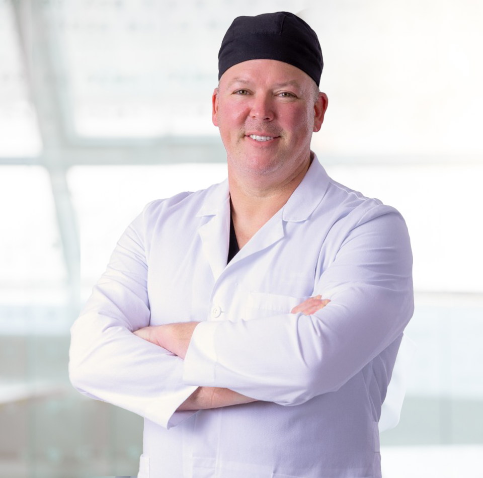 Dr. Oliver Pope Simmons, MD, Plastic and Reconstructive surgeon at BeautyLand Plastic Surgery Miami, is pictured posing with arms crossed and smiling for a picture.