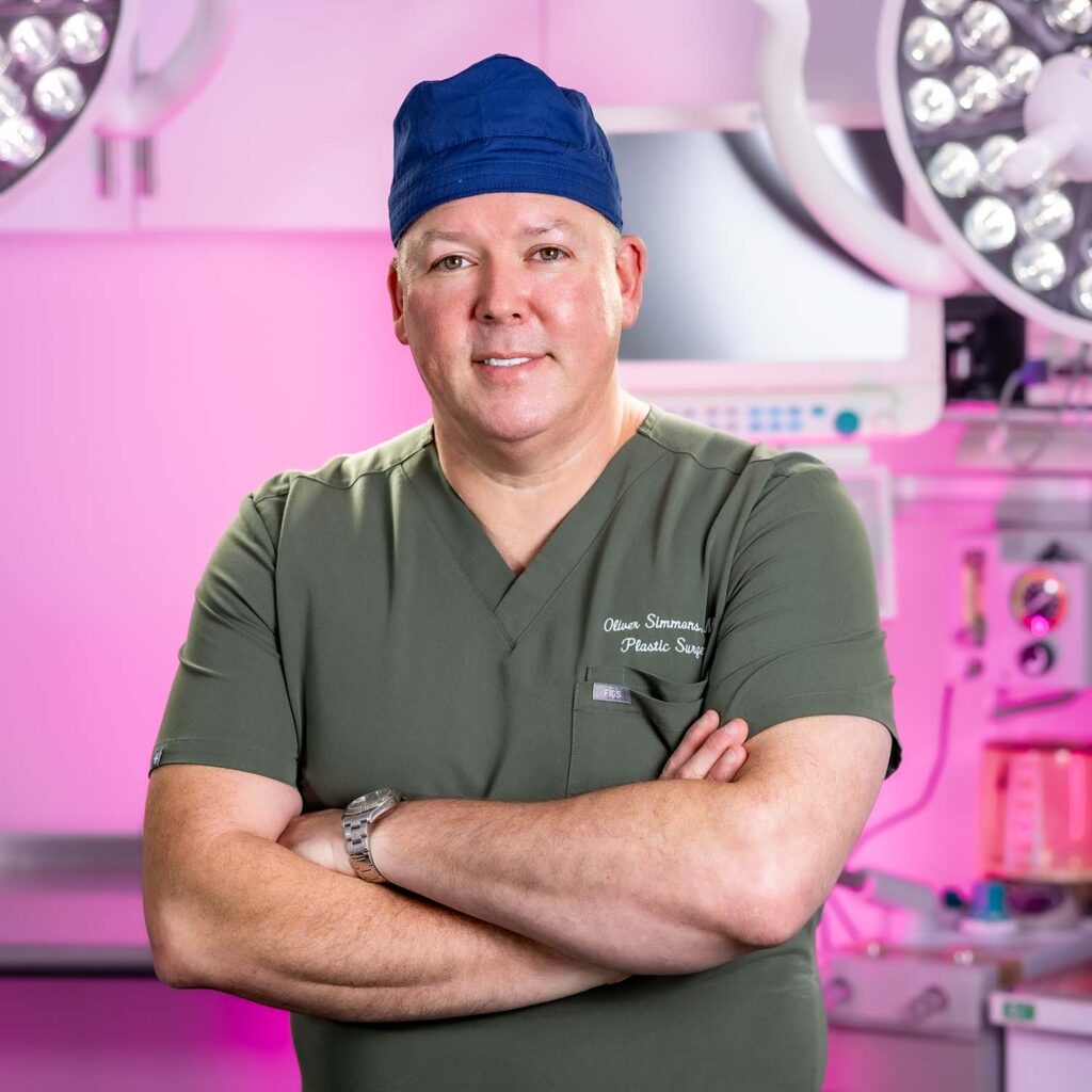 Dr. Oliver Pope Simmons, MD, Plastic and Reconstructive surgeon at BeautyLand Plastic Surgery Miami, is pictured posing with arms crossed and smiling for a picture.